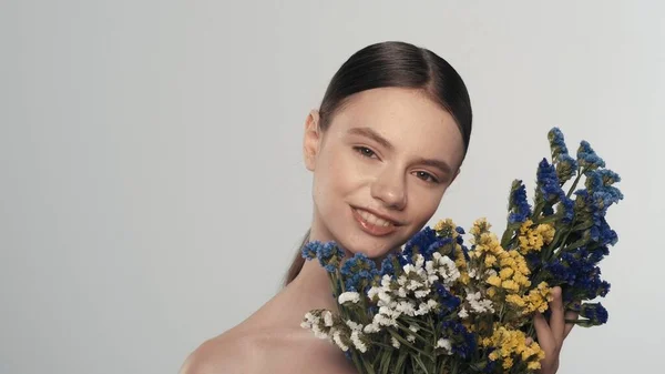一个有着柔和妆容的年轻女性模特的画像 一个女人的近照 带着一束五颜六色的干花在镜头前微笑 自然美广告概念 — 图库照片