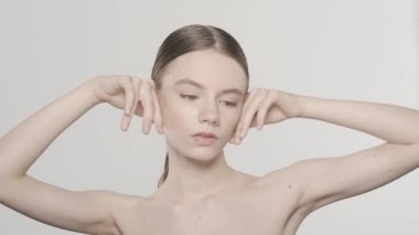 Çekici esmer bir kadın modelin portresi. Bir kadının kameraya bakarken, yüzüne dokunurken, elmacık kemikleri bölgesindeki pürüzsüz deriyi yakından çek. Güzellik derisi reklam konsepti. HDR BT2020