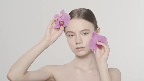 신선한 피부와 매력적인 모델의 초상화 그녀의 꽃으로 그녀의 얼굴을 만지는 — 비디오