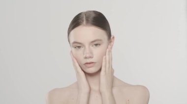 Güzel esmer bir kadın modelin portresi. Kameraya bakan bir kadının yakın çekim görüntüsü, pürüzsüz tenine, omzuna, boynuna ve yüzüne dokunuyor. Güzellik derisi reklam konsepti. Yavaş