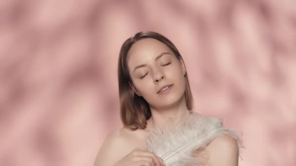 Una Donna Tocca Spalle Nude Viso Con Una Piuma Bianca — Video Stock