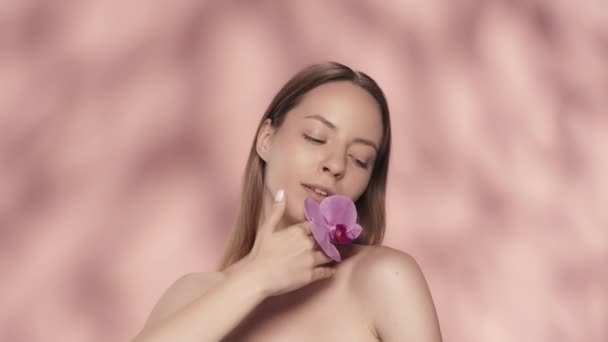 Kvinna Vidrör Orkidé Blomma Till Ren Hud Ansiktet Och Bara — Stockvideo