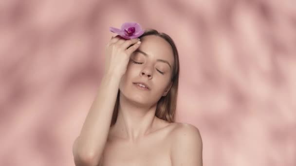 Eine Frau Berührt Eine Orchideenblume Auf Ihrer Sauberen Glatten Haut — Stockvideo