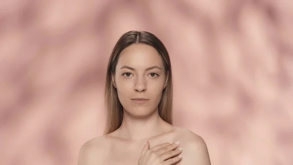 若い女性が肩に触れ 滑らかで柔らかい肌を楽しんでいる ピンクのバックグラウンドで孤立した女性の肖像画 化粧品 スキンケア スパのコンセプト — ストック写真