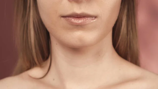 繊細なピンクの口紅が付いた女性の唇はピンクのぼやけた背景に閉じ込められています ポマード スキンケアのコンセプト — ストック写真