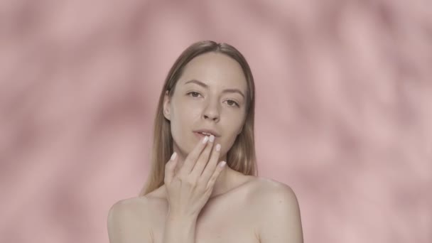 Uma Mulher Toca Seus Lábios Enquanto Hidrata Estúdio Fundo Rosa — Vídeo de Stock