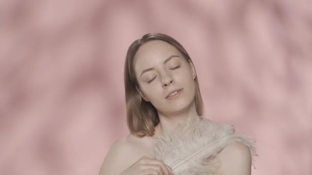 Woman Touches Her Bare Shoulders Face White Feather Young Woman — Stock Video