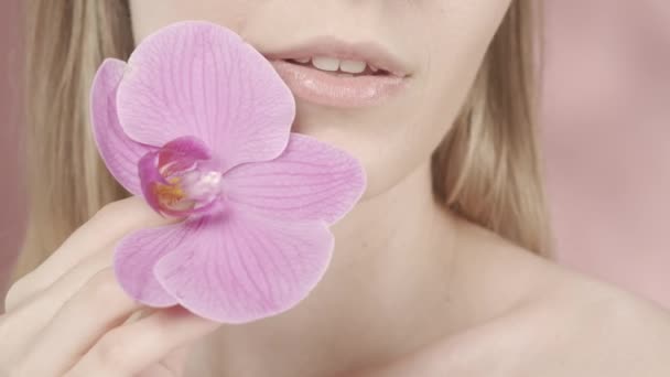 Női Ajkak Finom Rózsaszín Rúzzsal Orchideavirág Közelkép Rózsaszín Homályos Háttérrel — Stock videók