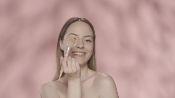 Χαρούμενη Φοιτήτρια Χαμογελαστή Χρησιμοποιεί Πινέλο Μακιγιάζ Στο Στούντιο Ροζ Φόντο — Αρχείο Βίντεο