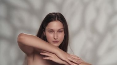 Genç, beyaz bir modelin portresi. Kameraya bakan bir kızı yakından çek, kolları çapraz, ellerinin pürüzsüz derisine dokunan, yüzünün olduğu yere. Güzellik sigortası reklam konsepti.