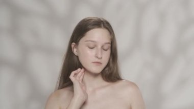 Doğal makyajlı genç bir modelin portresi. Kulağının arkasına çiçek koyan bir kızı yakından çek. Kameraya şakacı bir şekilde bakıp dudaklarına dokunuyor. Doğal güzellik reklamı konsepti. HDR