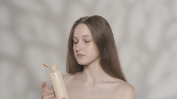 魅力的なブルネットモデルの肖像画 ボディクリームのボトルを持っている女の子の近くのショット 彼女はクリームを手に絞って匂いを嗅ぎます ビューティーボディケアの広告コンセプト Hdr Bt2020 Hlgについて — ストック動画