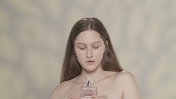 一个迷人的黑发模特的肖像 一个女孩拿着一瓶粉红色香水的特写镜头 她闻到了 然后喷在自己身上 香水广告的概念 Hdr Bt2020 Hlg Material — 图库视频影像