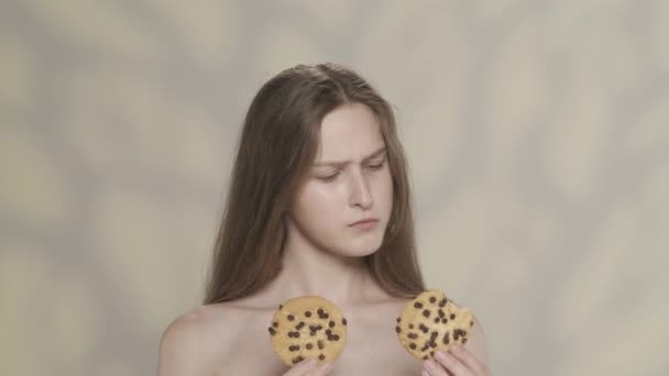 迷人的黑发模特的肖像 拍到一个女孩拿着两个饼干 然后决定吃哪一个 挑一个饼干 享受它的味道 节食广告的概念 Hdr — 图库视频影像