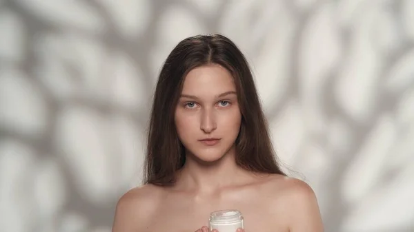 化粧品を保有する若手モデルの肖像画 長い髪と柔らかいメイクでカメラを見ている女の子 白い背景に孤立した スキンケア広告コンセプト — ストック写真