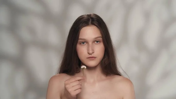 新鮮な肌を持つ若い女性の肖像画 カメラを見て 花を持っている少女のショットを閉じます ナチュラルビューティー広告コンセプト — ストック写真