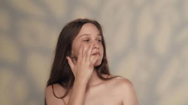 美しいブルネットモデルの肖像画 ヌードメイク ブルーの目をした女の子のクローズアップショット 彼女は目の下に滑らかな肌に触れている アイスキンケア広告コンセプト — ストック写真