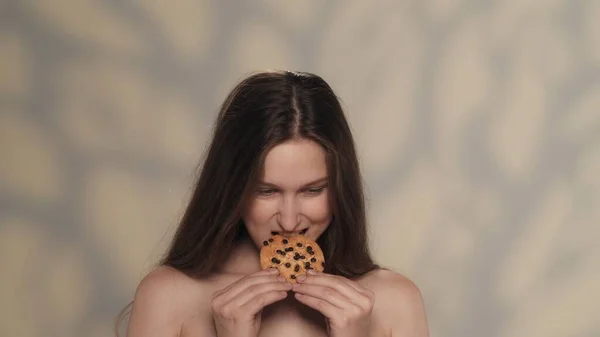 魅力的なブルネットモデルの肖像画 長い髪とチョコレートチップクッキーを食べる自然な化粧をした少女のショットを閉じます ダイエット広告コンセプト — ストック写真
