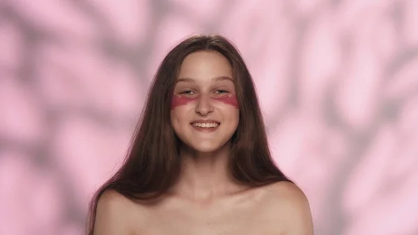 美しい白人モデルの肖像画 彼女の目の下にピンクの目パッチが付いている女の子の近くのショット カメラで笑顔で アイスキンケア広告コンセプト — ストック写真