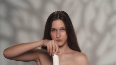 Çekici esmer bir mankenin portresi. Elinde bir şişe vücut kremi olan bir kızın kameraya bakarken yakın plan fotoğrafı. Güzellik sigortası reklam konsepti.