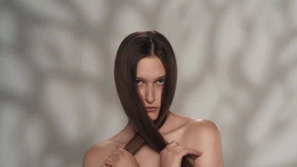 一个年轻女性模特的肖像 一个有着丝般长发的女孩的近照 她双手挽着头发 看着摄像机 美发广告概念 — 图库照片