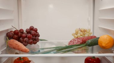 Kapalı bir buzdolabının rafındaki sağlıklı yiyecekler. Buzdolabının içinden görüntüle