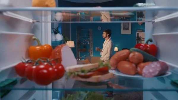 Raflarda Yiyecek Olan Bir Buzdolabı Bornozlu Bir Adam Elinde Bir — Stok fotoğraf