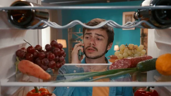 Egy Férfi Telefonnal Füléhez Nyitott Hűtőben Egy Férfi Ellenőrzi Ételt — Stock Fotó