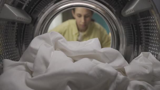 Ung Kvinna Med Tvättkorg Öppnar Dörren Till Tvättmaskinen Och Tar — Stockvideo