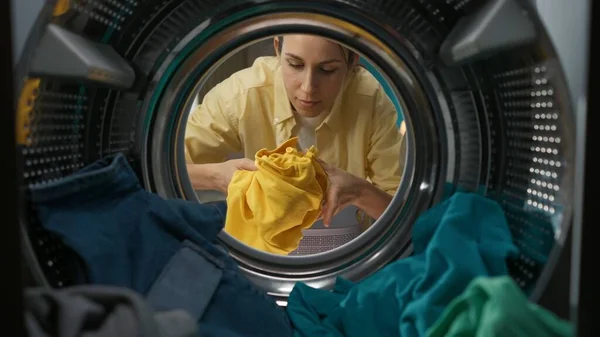 身穿便衣 提着洗衣篮的成年妇女打开洗衣机的门 拿出新衣服 从洗衣机内观看 — 图库照片