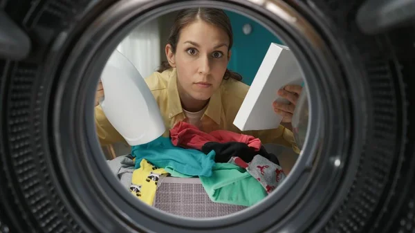 一个穿着休闲装的年轻成年女子的肖像 手里拿着一盒洗衣粉和织物柔软剂 从洗衣机内观看 — 图库照片