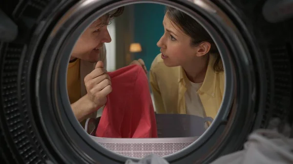若い男女がお互いを見つめあい 話し合い 服を手に持っている肖像画 一緒に洗濯をするカップル 洗濯機の中からの眺め — ストック写真