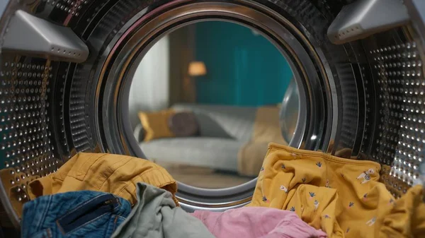 在开着门的鼓里 一个装有五颜六色衣服的洗衣机的特写镜头 每天洗衣服的日常概念 从洗衣机里看到一个空客厅 — 图库照片