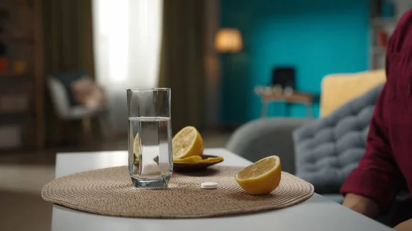 一张妇女坐在沙发上的特写照片 桌上放着一杯水 旁边放着柠檬和泡泡丸 家庭医学的概念 保健广告 — 图库照片
