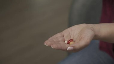 Kameraya elini gösteren bir kadın modelin yakın çekimi. Bir sürü renkli hap ve kapsül avucunun içine düşmeye başladı. Sağlık hizmeti reklamı. Yavaş çekim HDR BT2020 HLG Malzemesi.