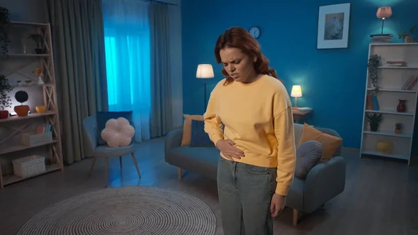 一个女人站在客厅里 双手捂住肚子 痛苦不堪 一个女人患有腹部疼痛 月经疼痛 消化不良 家庭医疗概念 — 图库照片