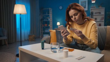 Mutsuz kadın kanepede oturmuş başını tutuyor. Bir kadın ne yazık ki çeşitli ilaçlara bakar, ilaçlarla kabarcıklar olur. Kadın hastaymış. Ev hekimi konsepti