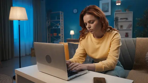 여자는 저녁에 거실에서 소파에 앉아있는 노트북에서 작동합니다 이메일 온라인 — 스톡 사진