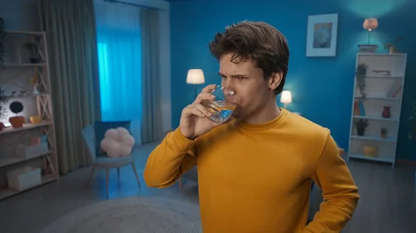 Ein Mann Trinkt Wasser Mit Zitrone Während Abends Wohnzimmer Steht — Stockfoto
