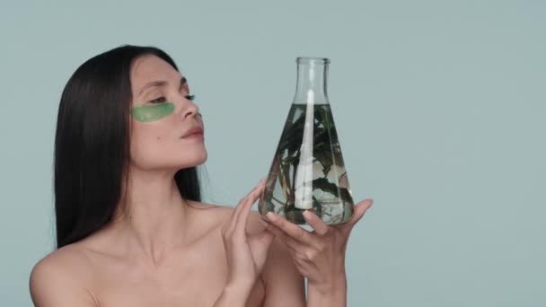 Kvinna Med Gröna Hydrogelplåster Ögonen Håller Kolv Med Växt Seminarium — Stockvideo