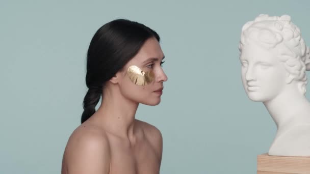 Woman Golden Patches Her Eyes Looks Female Plaster Bust Front — Stock Video