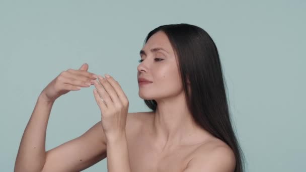 Uma Mulher Aplica Esfrega Creme Pele Suas Mãos Fundo Azul — Vídeo de Stock