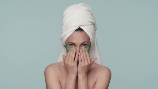 一名头戴毛巾的妇女在洗了一个蓝色背景的淋浴后做了整容手术 嘴上有斑斑的女人 眼皮底下有光滑斑斑的女人 美的概念 — 图库视频影像