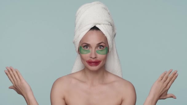頭にタオルをかけた女性は 手を顔から取り出して開けます そして女性のハイドロゲルパッチの目の下の女性化粧品の手順 美のコンセプト — ストック動画
