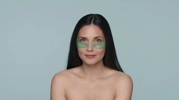 布鲁内特女人做面部皮肤护理 在一个蓝色背景的工作室里 一个有着绿色水凝胶斑斑的具有种子的女人的画像 美的概念 — 图库照片