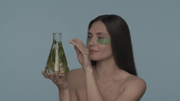 Kvinna Med Gröna Hydrogelplåster Ögonen Håller Kolv Med Växt Seminarium — Stockvideo