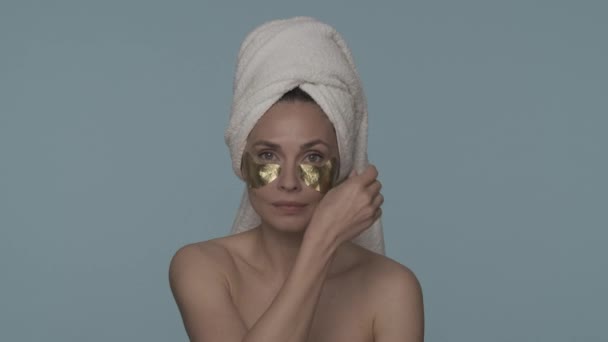 Uma Mulher Remove Manchas Douradas Pele Sob Olhos Fundo Azul — Vídeo de Stock