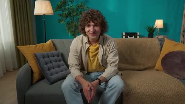 Oturma Odasındaki Kanepede Oturan Rahat Giyimli Mutlu Genç Bir Erkek — Stok video