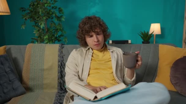 Oturma Odasındaki Kanepede Oturmuş Kitap Okuyan Gündelik Elbiseli Genç Bir — Stok video