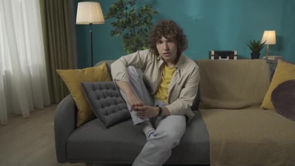 Oturma Odasındaki Kanepede Bacağı Kalkık Ciddi Bir Yüzü Olan Gündelik — Stok video